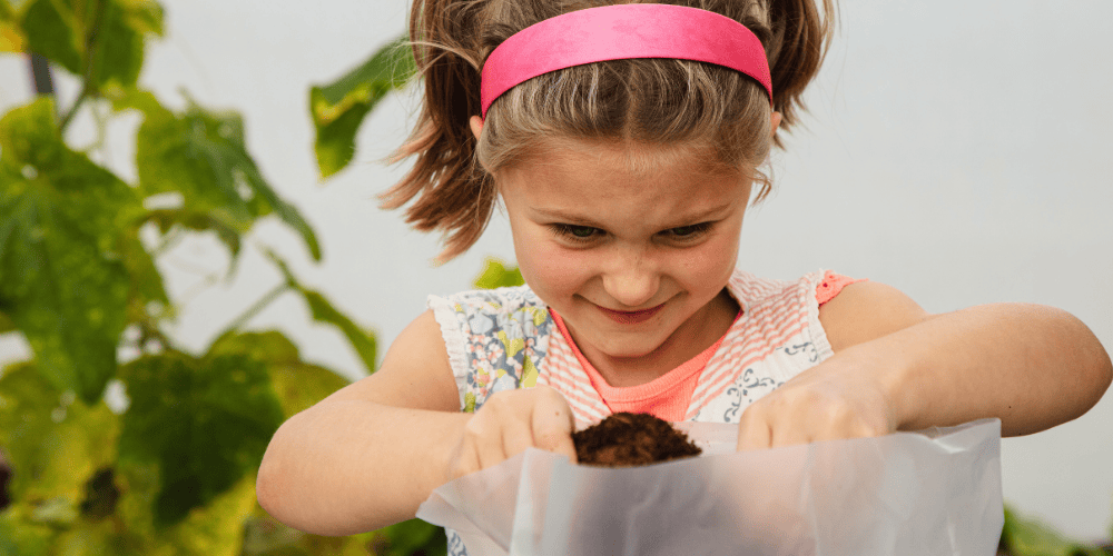 Young girl holding a small animal in a garden setting