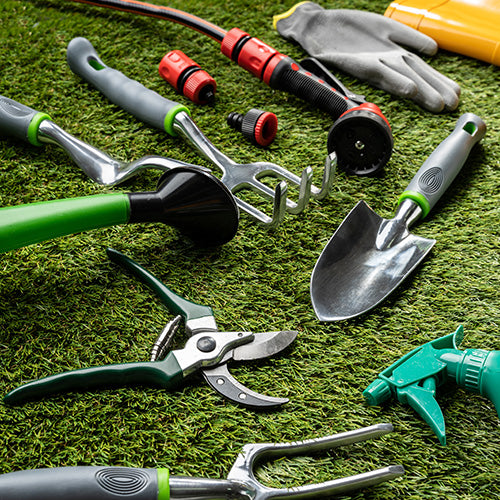 A selection of popular garden tools laid out on grass after being cleaned.