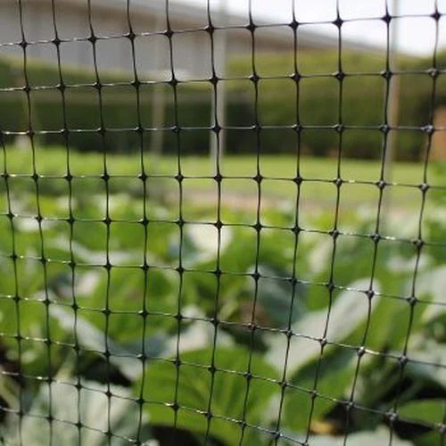 Close-up of a black wire mesh with a blurred green background