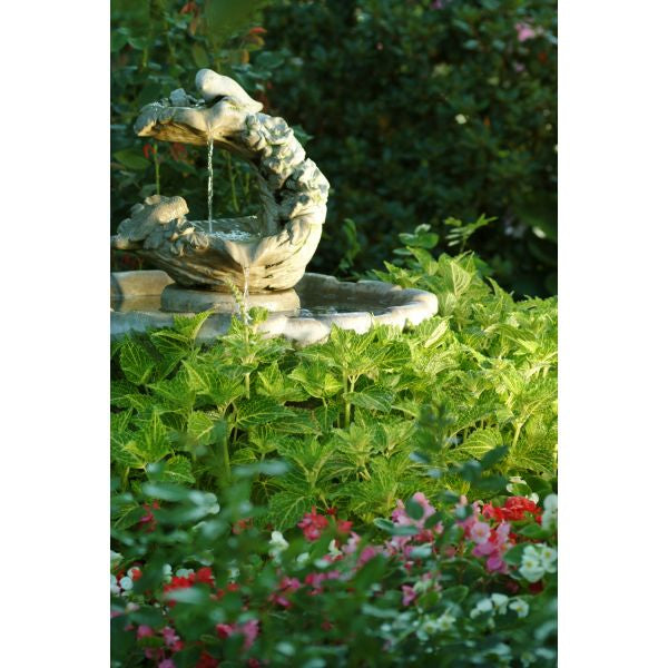 Garden fountain with birds surrounded by greenery and flowers