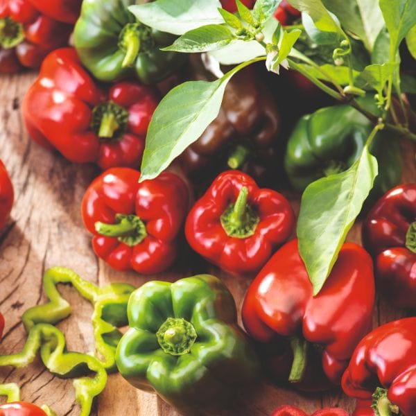 Red and green bell peppers on a wooden surface
